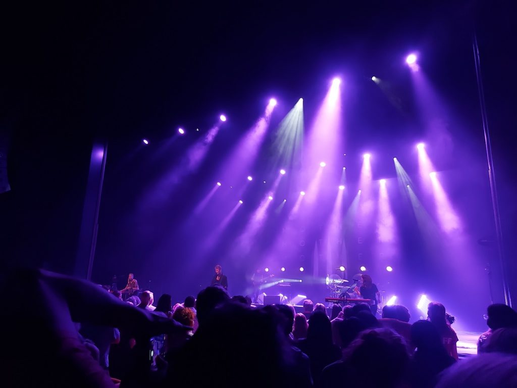 View of the members of Mother Mother on stage, lit up in purple lights.