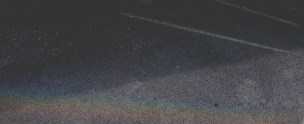 A rainbow and three faint bands of light cross the image diagonally against a dark concrete background.