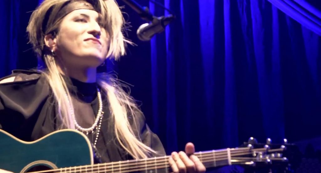 Live photo of Saga holding an acoustic guitar just before playing a song, taken during the 2021 Saga Birthday Festival concert.